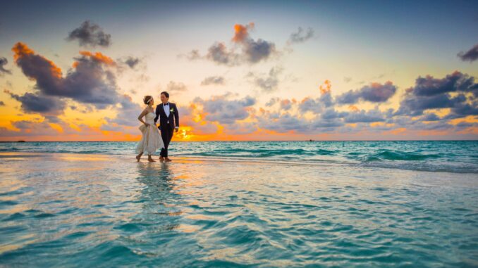 Bride and groom walking on the beach at sunset
